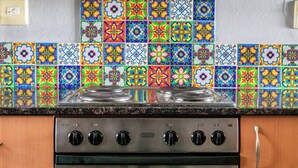 Une cuisine avec des carreaux de céramique aux couleurs vives, un fourneau et des armoires en bois.