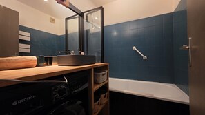 A modern bathroom with a large mirror, a sink, and a bathtub.