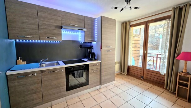 A modern kitchen with a built-in dishwasher, a coffee maker, and under-cabinet lighting. - Cozy apartment in Briançon, close to the slopes (Briançon)