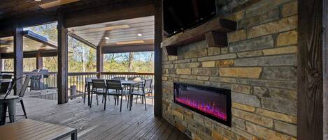 Un patio exterior con suelo de madera, paredes de piedra y chimenea integrada.