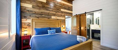 A bedroom with a wooden headboard, a blue bedspread, and a pillow with the text "GONE FISHING".