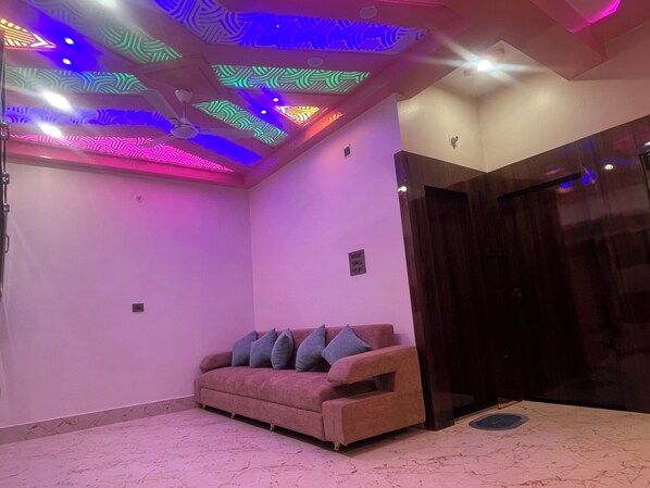 A room with a pink sofa, a ceiling with colorful lighting, and a dark wooden door.