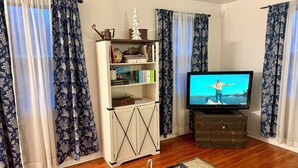 Una sala de estar con televisor, aparador de madera y estantería.