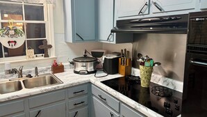 Una cocina con armarios blancos, una estufa negra y un fregadero.