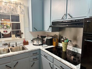A kitchen with white cabinets, a black stove, and a sink.