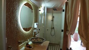 Une salle de bain avec un miroir rond, un lavabo, une douche et des carreaux de sol à motifs.