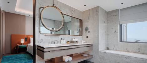 A modern bathroom with a large mirror, a bathtub, and a vanity with a countertop.