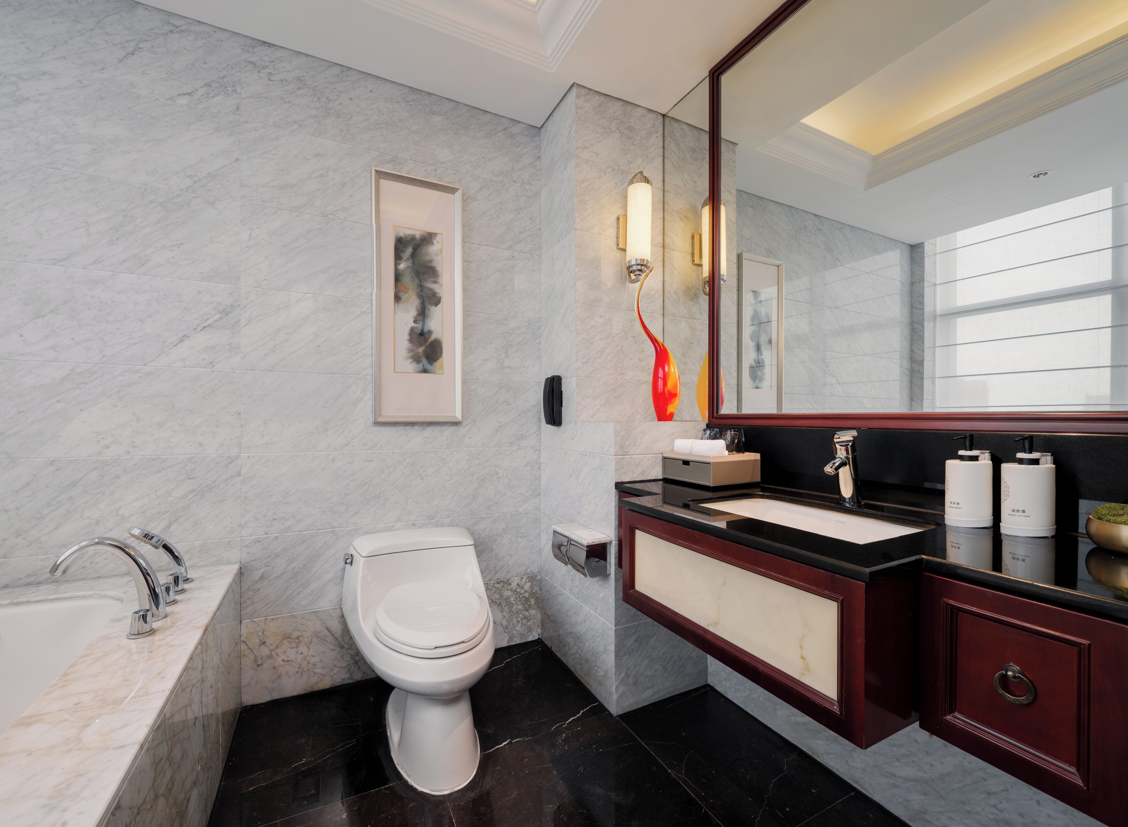 Une salle de bain moderne avec un sol en marbre, des toilettes blanches, un meuble-lavabo noir et un grand miroir.