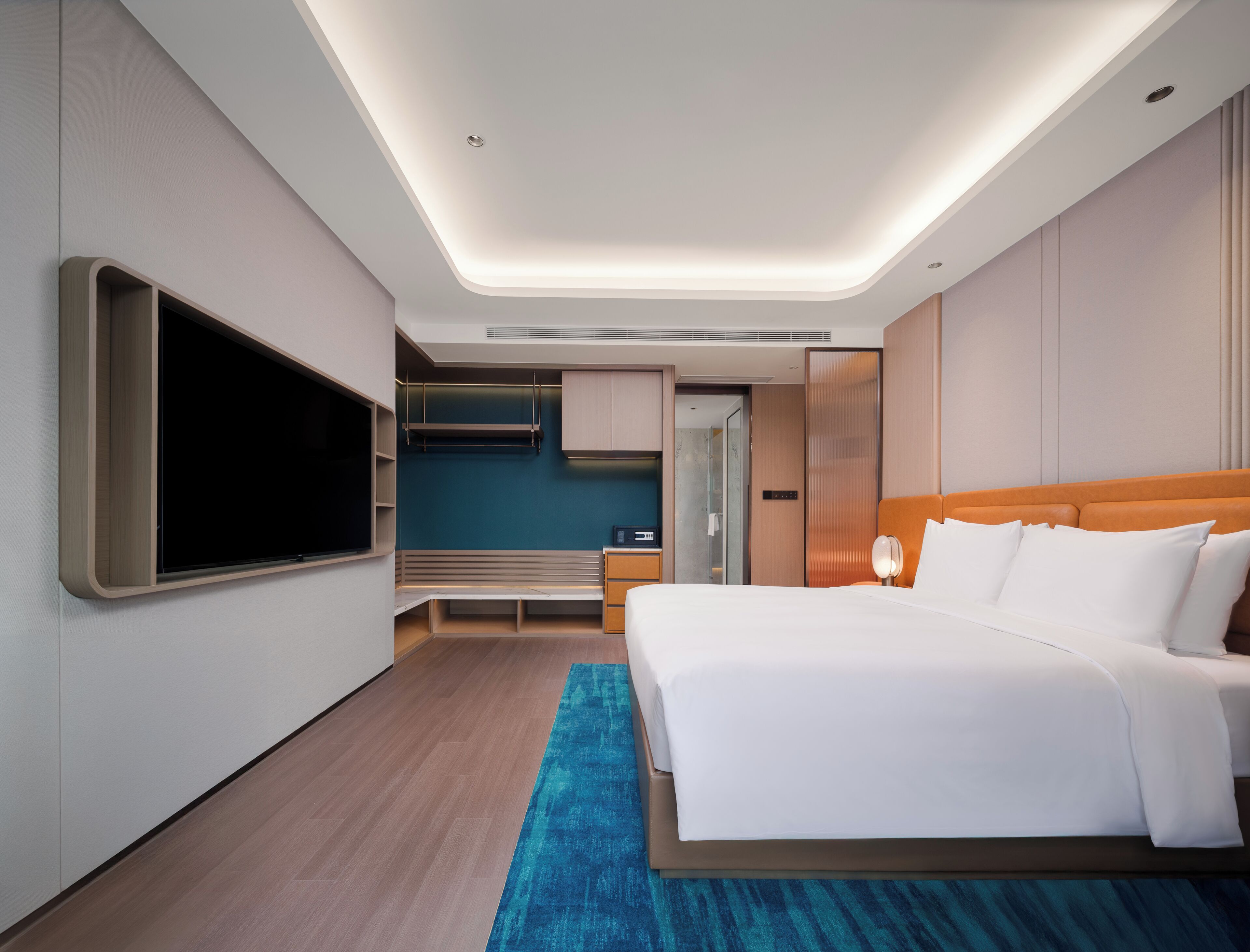 Quarto de hotel moderno com uma cama grande, televisão de tela plana, escrivaninha e closet espaçoso.