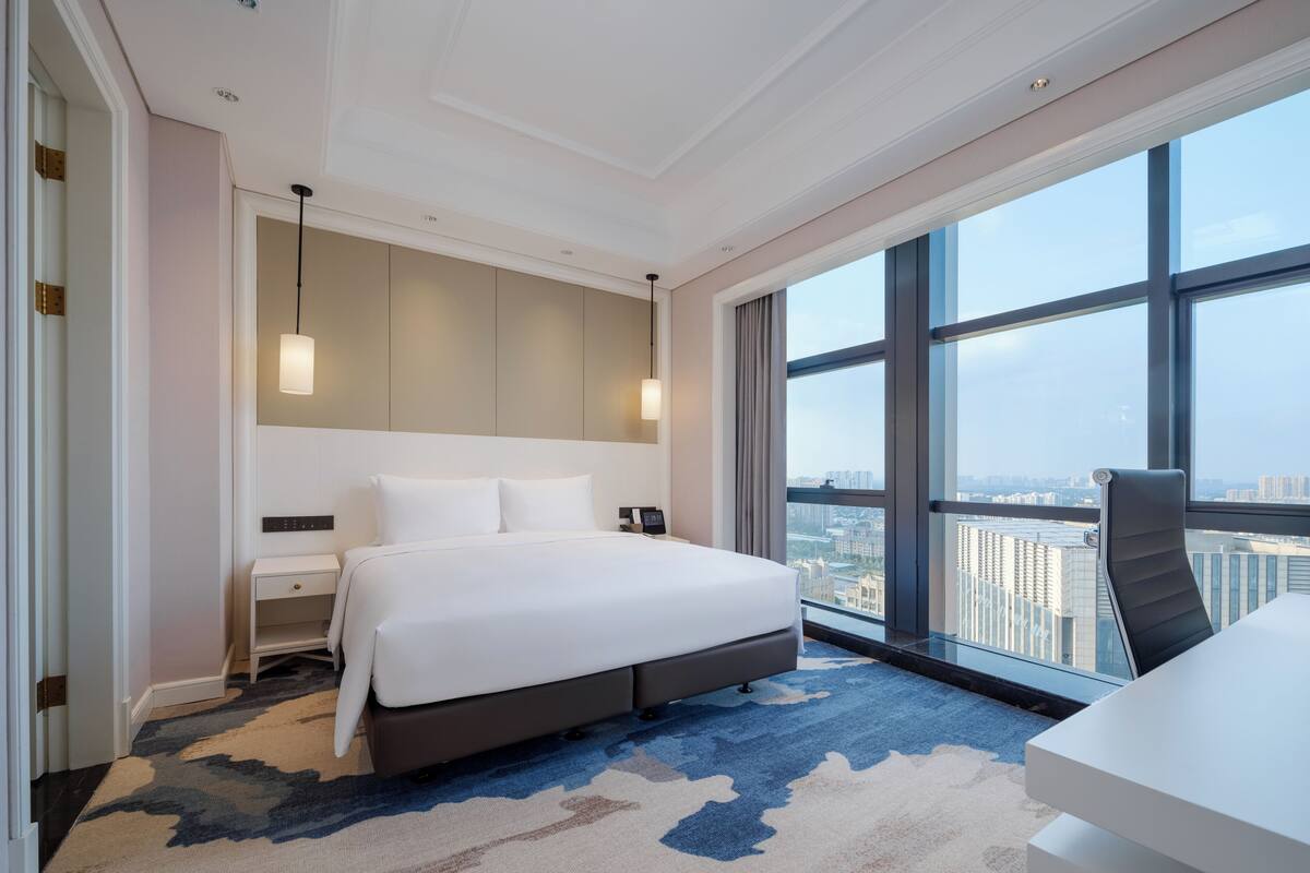 Una habitación de hotel moderna con una cama grande, una mesita de noche y un escritorio.