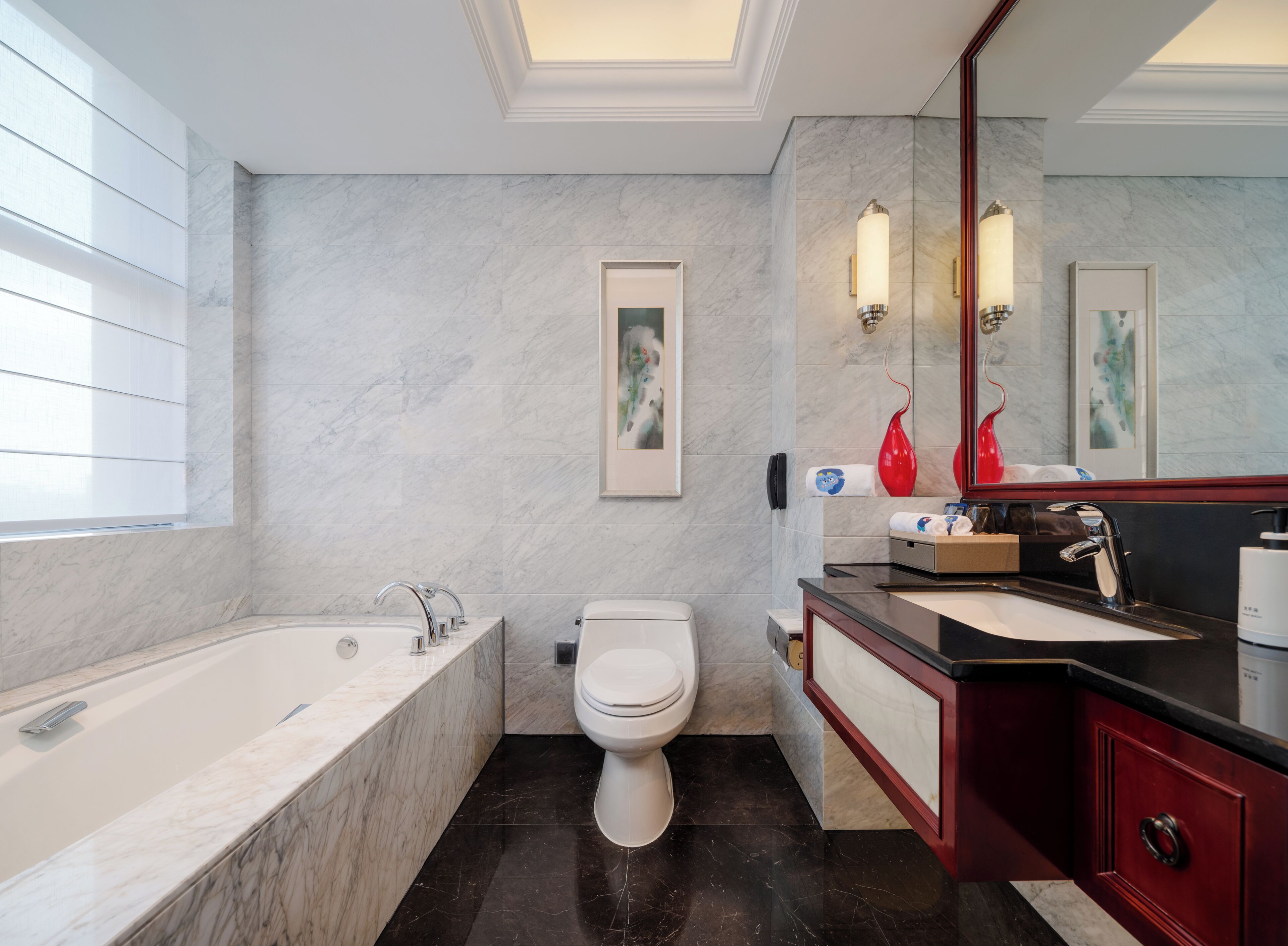 A modern bathroom with a bathtub, toilet, and vanity with a mirror.