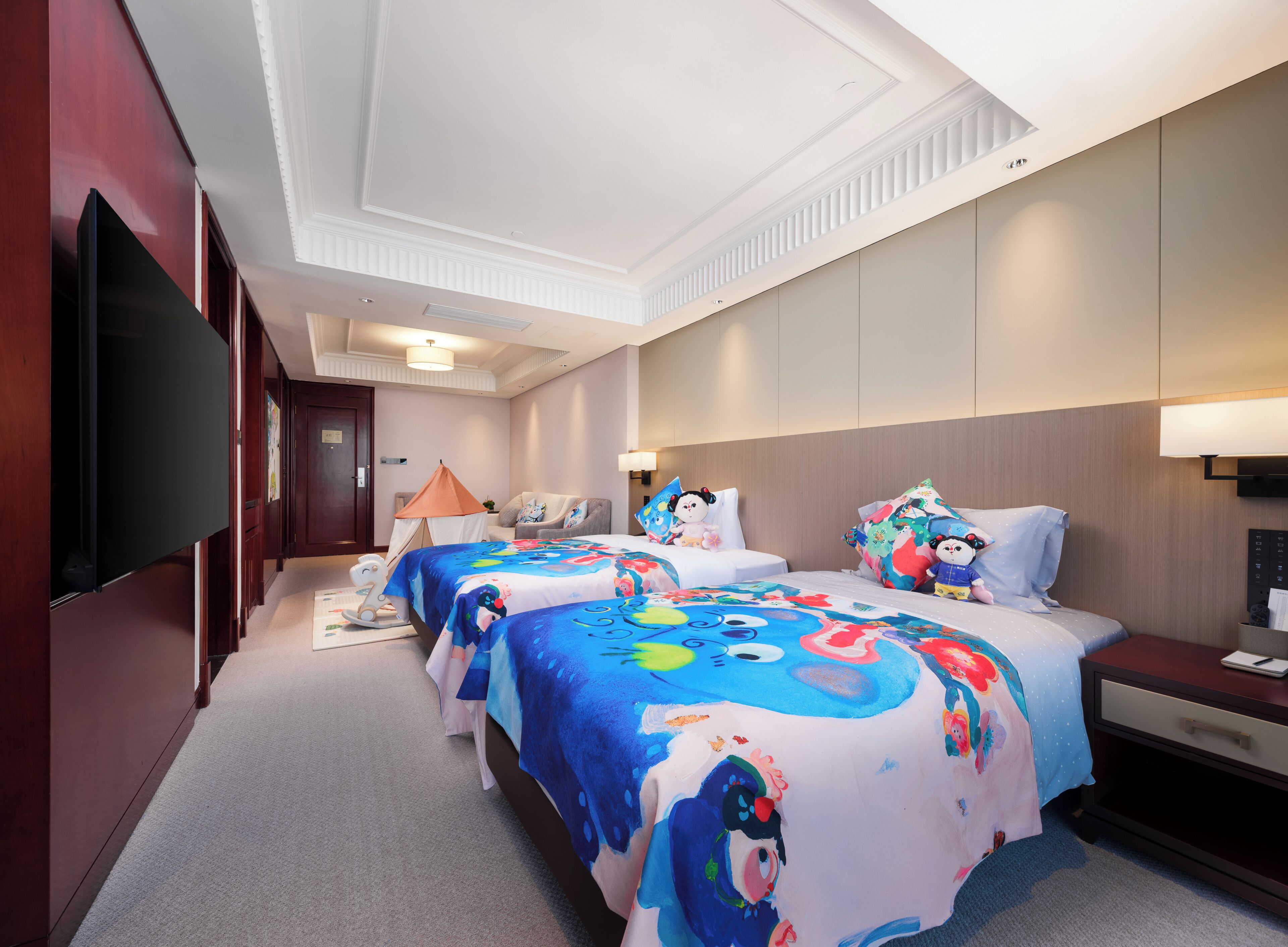 Een hotelkamer met twee bedden, een televisie, een bureau en een stoel.