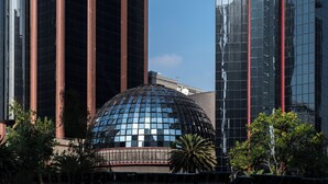 Un bâtiment moderne doté d’une structure en forme de dôme réfléchissant, entouré de gratte-ciel imposants.