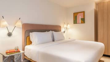 A neatly made bed with white linens, a marble side table with a book and a glass, and wall-mounted lamps.