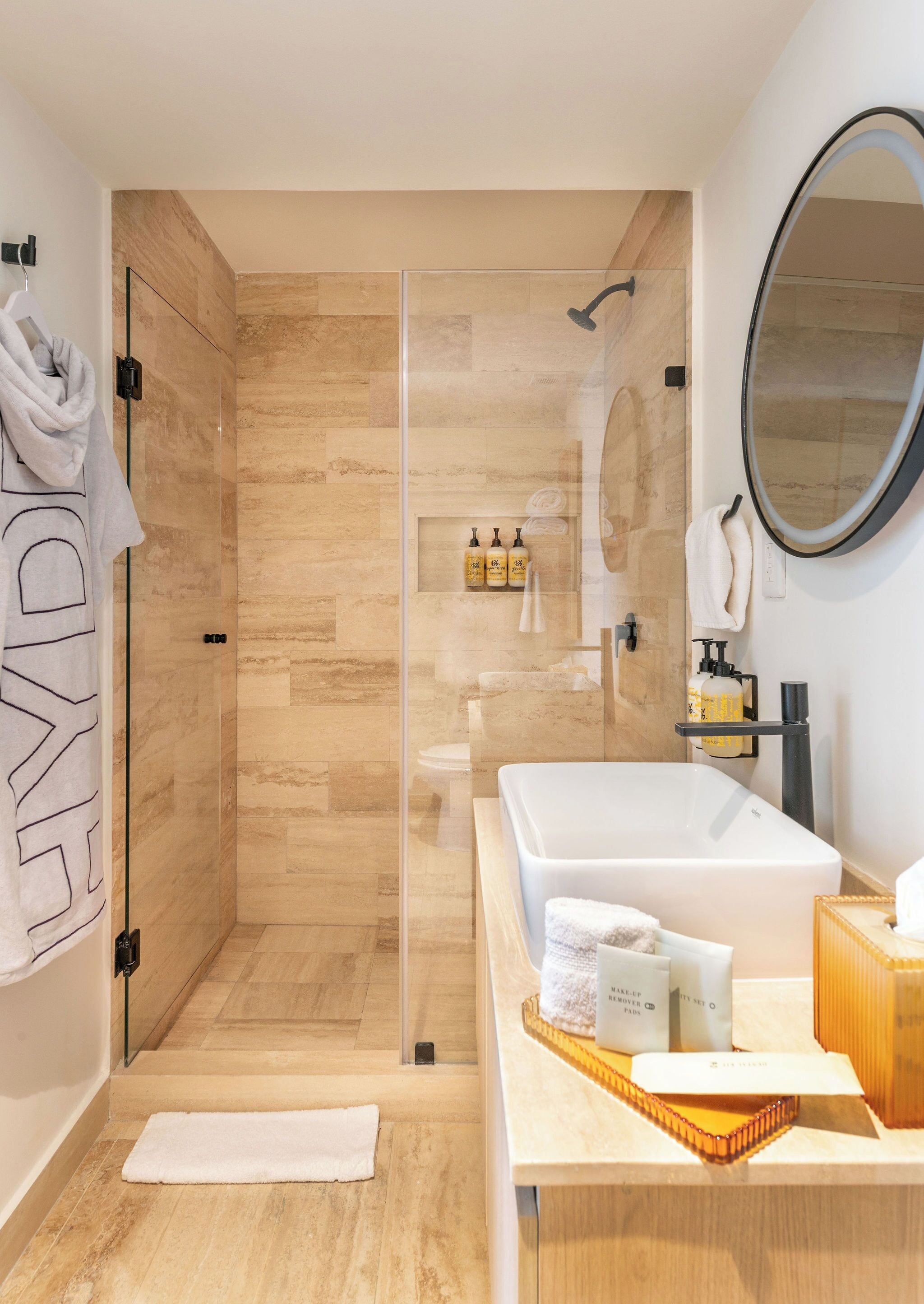 Un baño moderno con ducha de vidrio, una bañera blanca grande y un tocador con artículos de aseo.