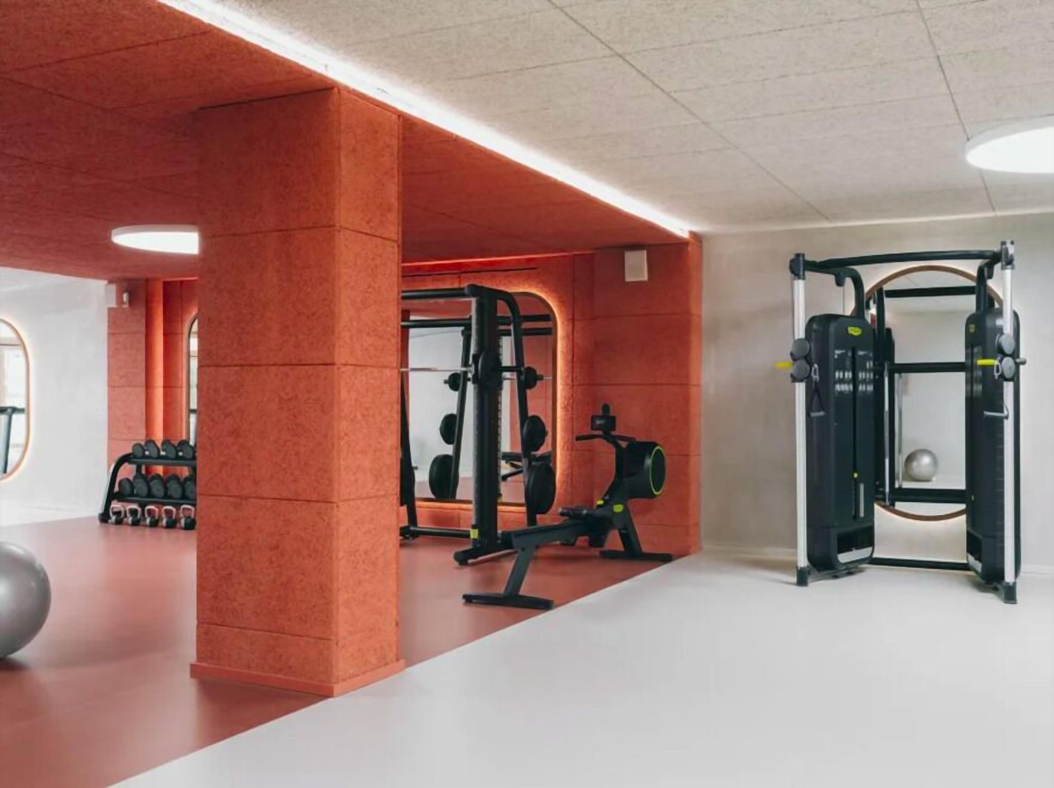 Un gimnasio con equipo de ejercicio, un soporte para pesas y un espejo grande.