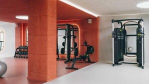 Een sportschool met trainingsapparatuur, een gewichtrek en een grote spiegel.