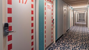 A hotel corridor with doors numbered 117 and 115, featuring a patterned floor and a modern design. - ibis budget Pontorson Baie du Mont-Saint-Michel (Saint-Georges-de-Grehaigne)