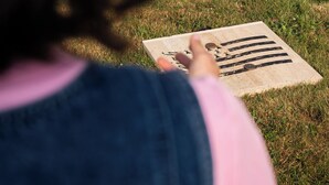 A person pointing at a wooden board with black symbols on a grassy area. - ibis budget Pontorson Baie du Mont-Saint-Michel (Saint-Georges-de-Grehaigne)