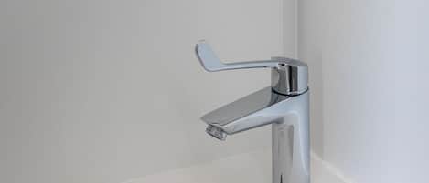 Un lavabo de salle de bain moderne, doté d’un robinet chromé et d’un miroir placé au-dessus.