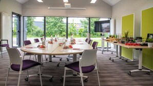 A conference room with a large table, chairs, and a projector. - ibis budget Pontorson Baie du Mont-Saint-Michel (Saint-Georges-de-Grehaigne)