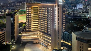 A high-rise hotel with a prominent 'NOVOTEL' sign, multiple floors, and a well-lit facade. - Novotel Zhoushan Luting (Zhoushan)