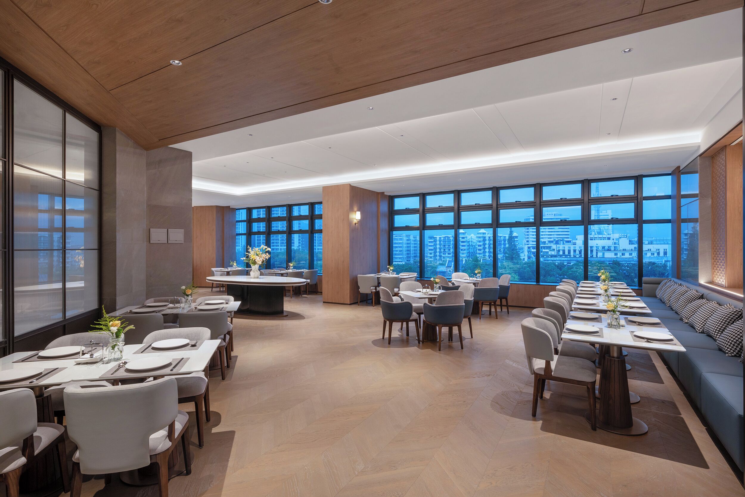 A modern dining area with long tables, chairs, and a sofa.