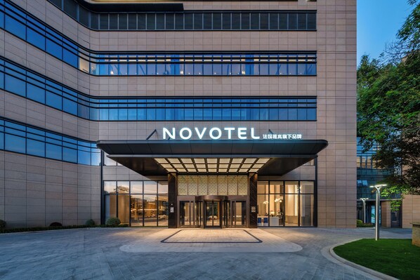 A modern hotel entrance with a glass facade, a prominent sign reading "NOVOTEL," and a well-lit entrance area. - Novotel Zhoushan Luting (Zhoushan)