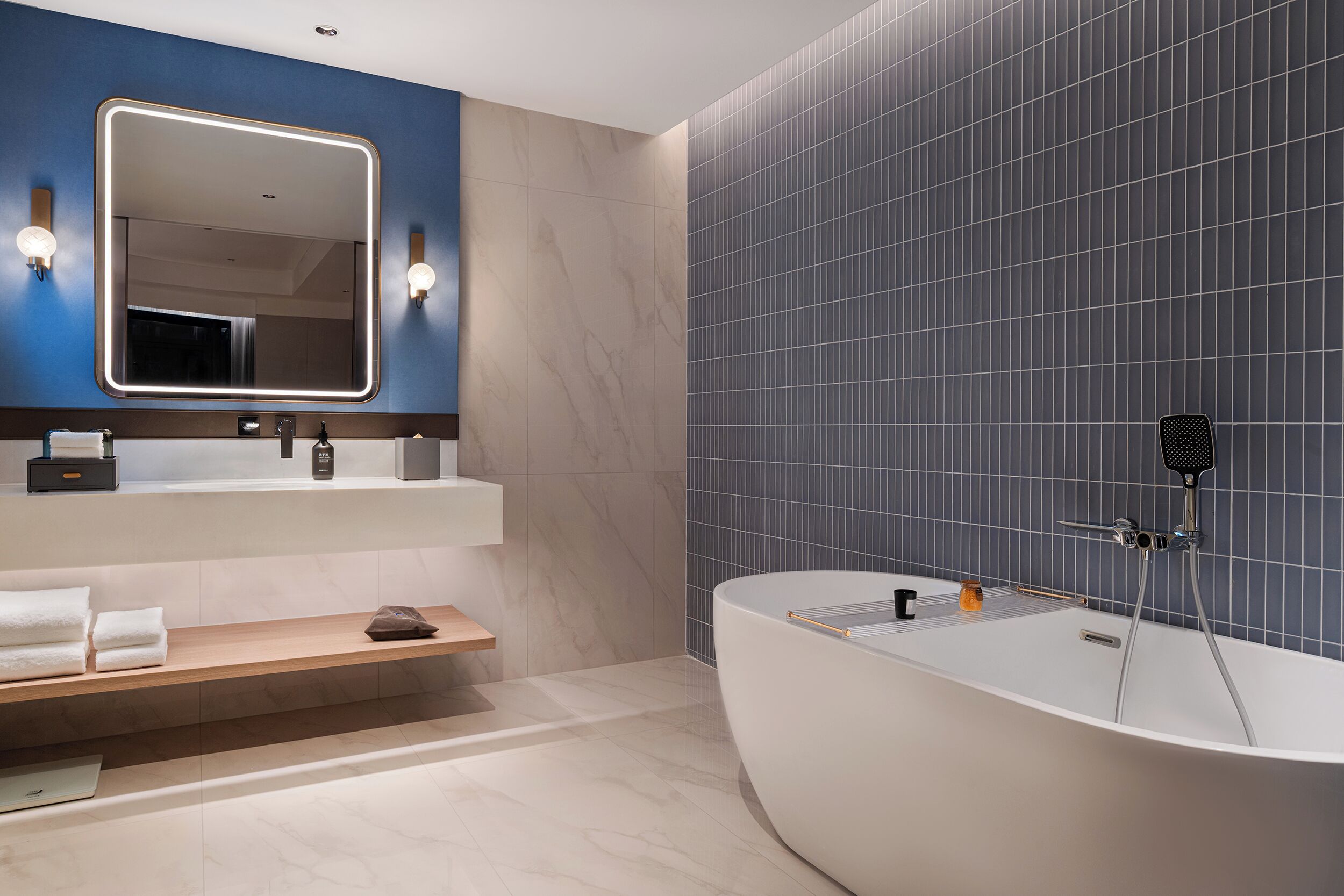 Une salle de bain moderne avec une baignoire sur pieds, un grand miroir et un meuble-lavabo doté d’un porte-serviettes.