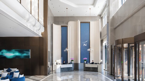 A modern hotel lobby with a reception desk, seating area, and a large digital display. - Novotel Zhoushan Luting (Zhoushan)