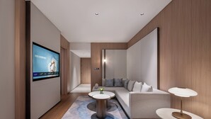 A modern living room with a flat-screen TV, a sofa, two side tables, and a patterned rug. - Novotel Zhoushan Luting (Zhoushan)