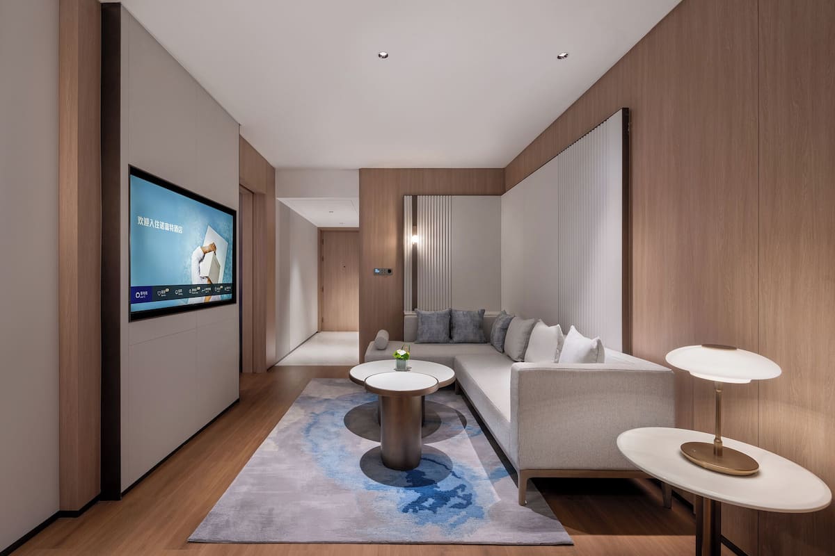 A modern living room with a flat-screen TV, a sofa, two side tables, and a patterned rug.