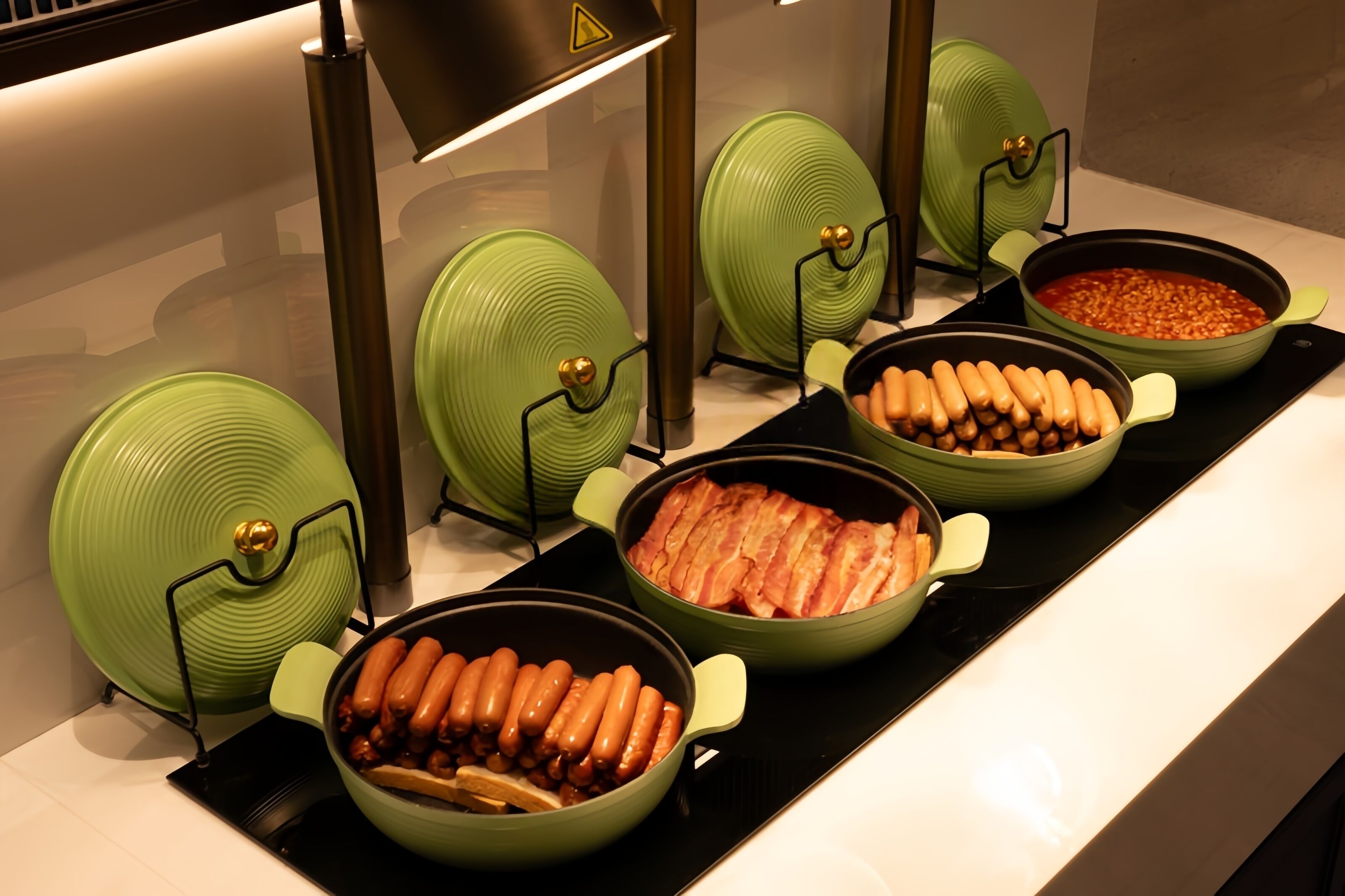 Un buffet proposant divers plats, notamment des saucisses et des haricots servis dans des pots verts.