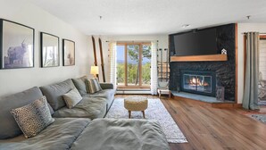 Ein Wohnzimmer mit einer Couch, einem Kamin und einem Fernseher.