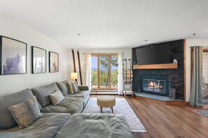 A living room with a sofa, a fireplace, and a television. - Obertal - Prime Slope-Side Condo at Stratton (Stratton)