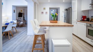 Una cocina moderna con armarios blancos, una isla de madera y un horno empotrado.