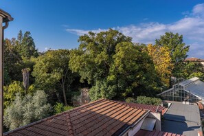 A rooftop with terracotta tiles, surrounded by dense green trees and a clear blue sky. - Santa Maria Dreaming Rooftop (Pisa)