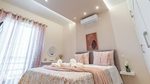 Un dormitorio con cama, mesita de noche, espejo y unidad de aire acondicionado.