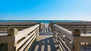 Pasarela de madera que conduce a una playa con cielos despejados.