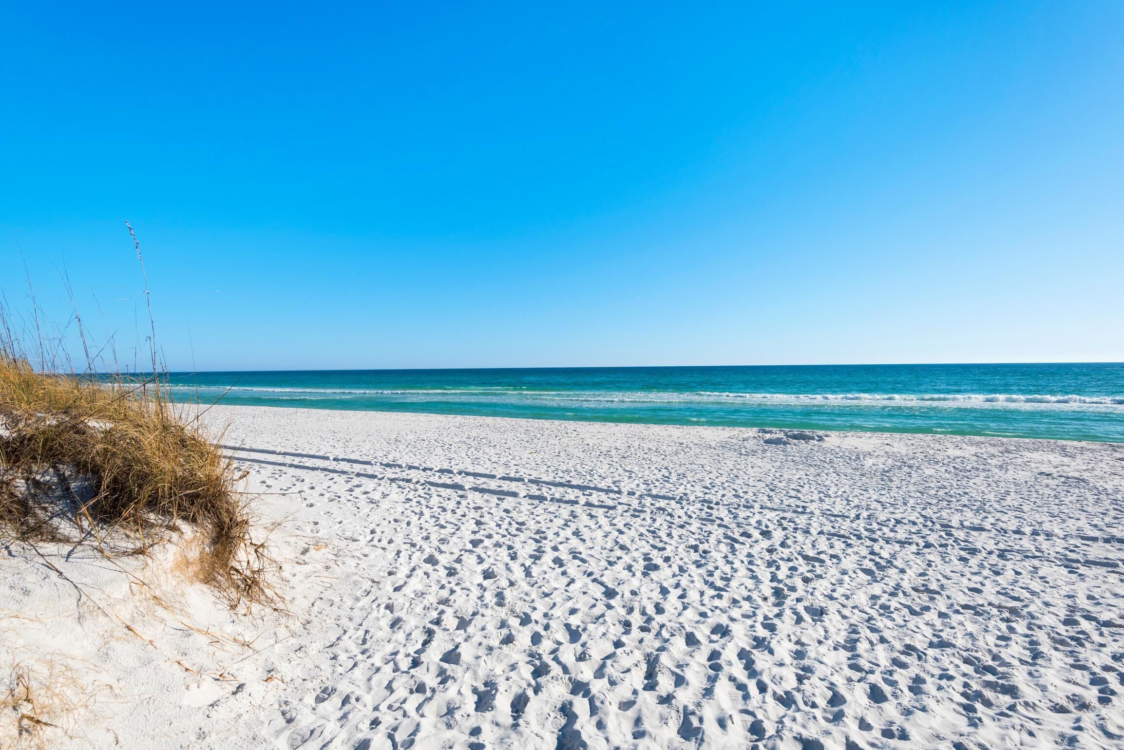 A sandy beach with clear blue water and a clear sky.