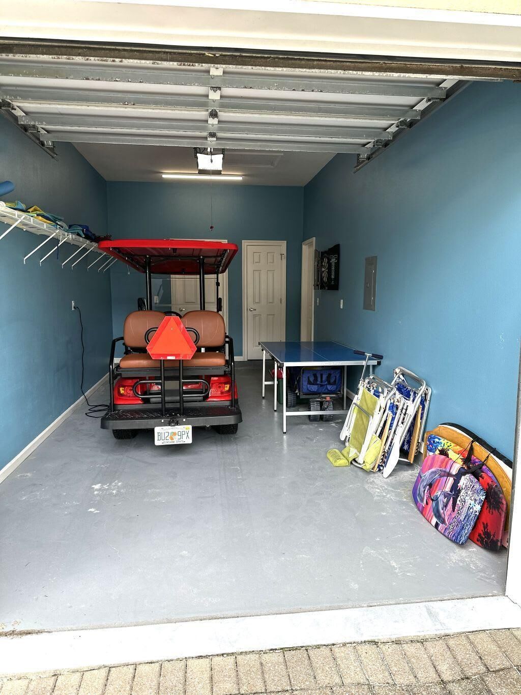 Un garage équipé d’un véhicule de golf, d’une table de ping-pong et d’une planche de surf.