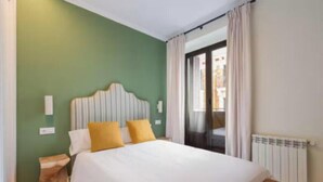 A bedroom with a bed, a nightstand, a wooden bench, a radiator, and a view of the outside. - Bright & Spacious 3-Bedroom Apartment in the Heart of Madrid (Madrid)