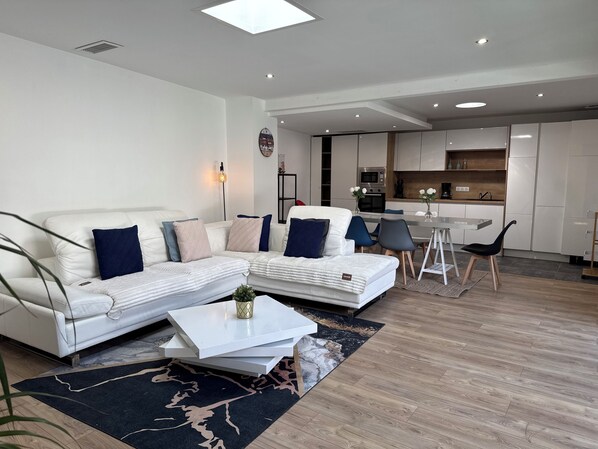 A modern living room with a sectional sofa, a coffee table, and a dining area with chairs. - Villa 400 m from the beach (Labenne)