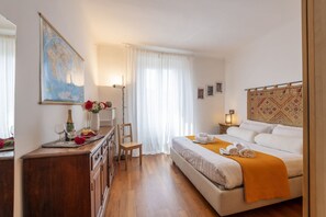 A hotel room with a bed, a wooden dresser, a desk, a chair, a map on the wall, and a window with curtains. - Paolo Sarpi, 36 - Milan Inside (Milan)