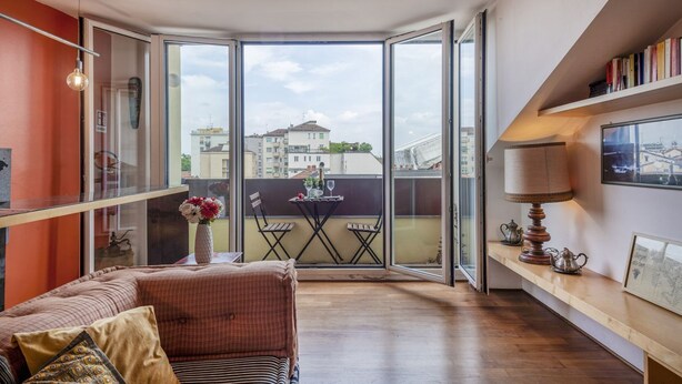 Ein modernes Wohnzimmer mit einer Couch, einem Tisch mit Stühlen, einer Lampe und einem Bücherregal.