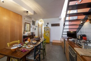 A compact kitchen with a dining area, a yellow refrigerator, and a TV. - Paolo Sarpi, 36 - Milan Inside (Milan)