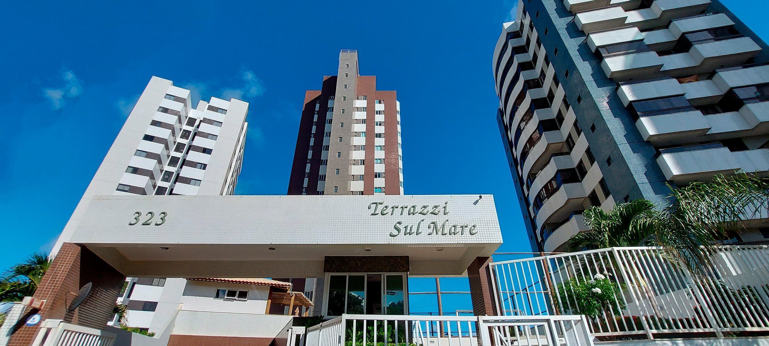 Un edificio moderno con el número 323, llamado 'Terrazzi Sul Mare', que presenta un balcón destacado y una vista despejada del cielo.