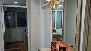 Un couloir doté d’un plancher en bois, d’un miroir et de deux bougies allumées posées sur une console en bois.