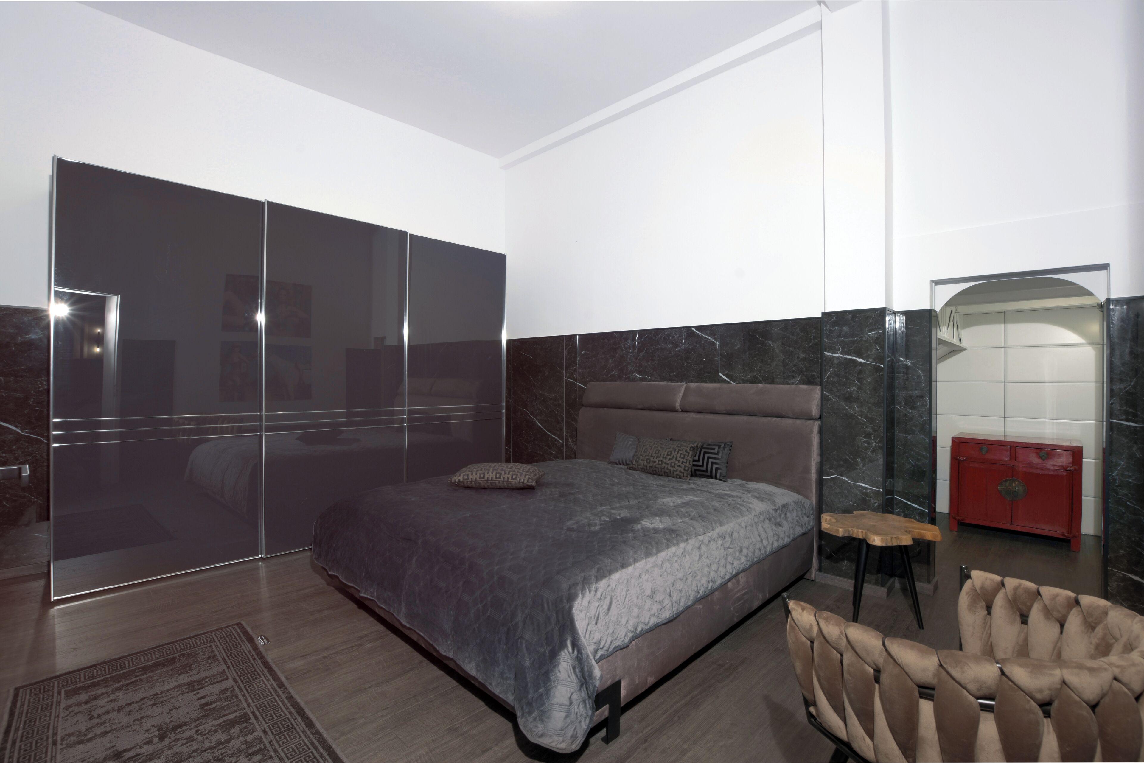Une chambre à coucher moderne avec un grand lit, une table de chevet en bois et une commode rouge.