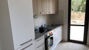 Une cuisine moderne avec des meubles blancs, un plan de travail noir et un four encastré.